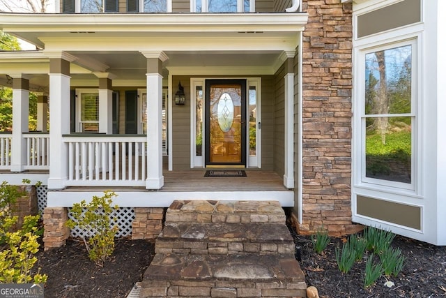 view of exterior entry featuring a porch and stone siding