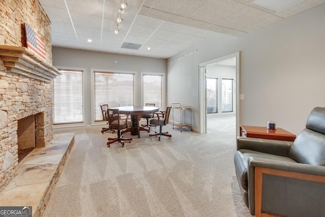 dining space with a stone fireplace, a wealth of natural light, a paneled ceiling, and carpet floors