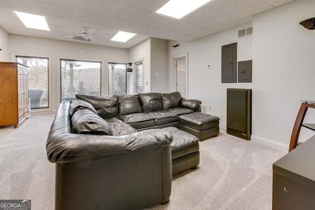 living room with electric panel, visible vents, light colored carpet, and a paneled ceiling