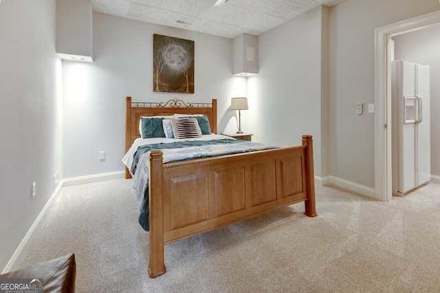 bedroom with white refrigerator with ice dispenser, light colored carpet, and baseboards