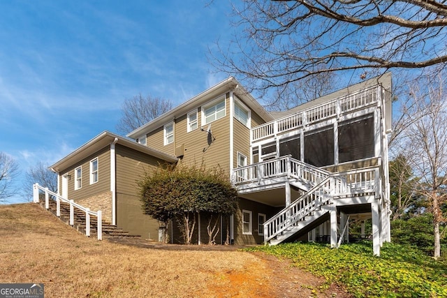 view of side of home featuring a lawn, stairs, and a sunroom