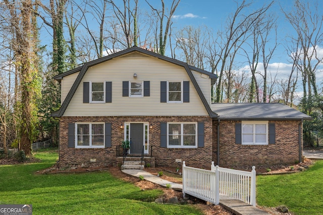 view of front of house featuring brick siding, a gambrel roof, and a front yard