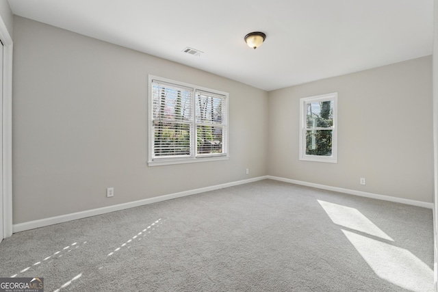 empty room with visible vents, plenty of natural light, baseboards, and carpet floors