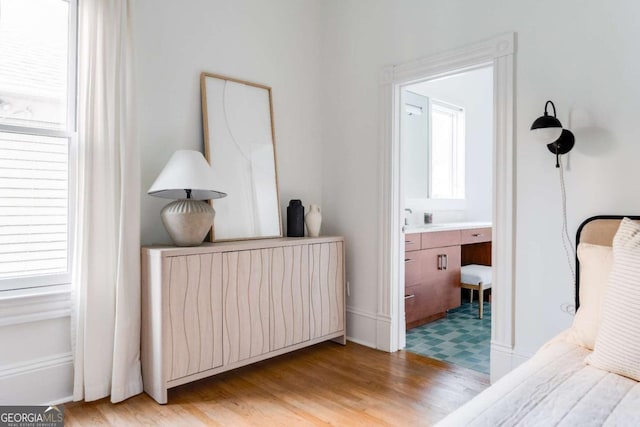 bedroom featuring light wood-style flooring and connected bathroom