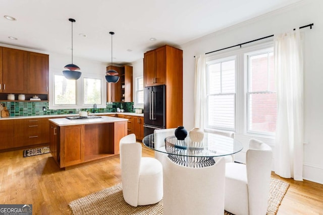 kitchen with brown cabinetry, light wood-style flooring, light countertops, high end refrigerator, and backsplash