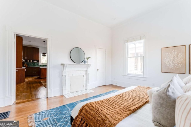 bedroom with a fireplace, wood finished floors, visible vents, and baseboards