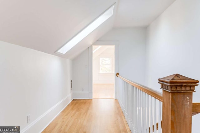 additional living space featuring baseboards, lofted ceiling with skylight, and wood finished floors