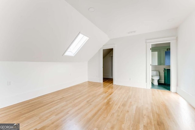 bonus room featuring visible vents, vaulted ceiling with skylight, and wood finished floors