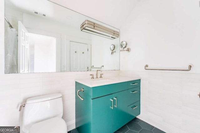 bathroom featuring tile patterned flooring, visible vents, toilet, vanity, and tile walls