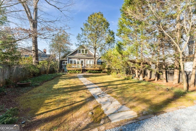 view of front facade with a fenced backyard, a wooden deck, and a front yard