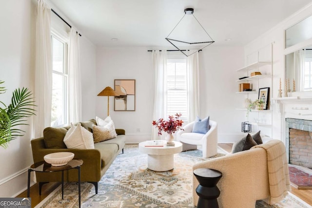 living area featuring a brick fireplace, baseboards, and wood finished floors