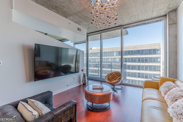 living room with a notable chandelier, a wall of windows, visible vents, and wood finished floors