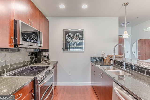 kitchen with a sink, light wood-style floors, appliances with stainless steel finishes, and brown cabinetry