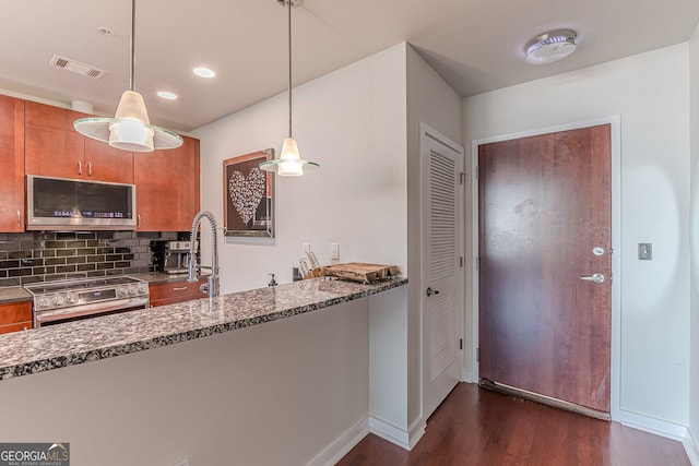 kitchen featuring visible vents, brown cabinets, dark wood-type flooring, stainless steel appliances, and stone counters