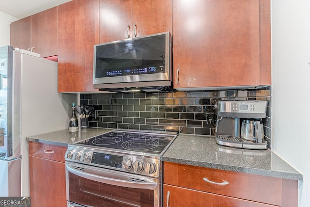 kitchen featuring decorative backsplash, dark stone countertops, brown cabinets, and appliances with stainless steel finishes