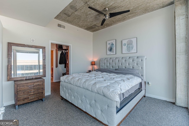 bedroom with baseboards, visible vents, carpet floors, ceiling fan, and a walk in closet