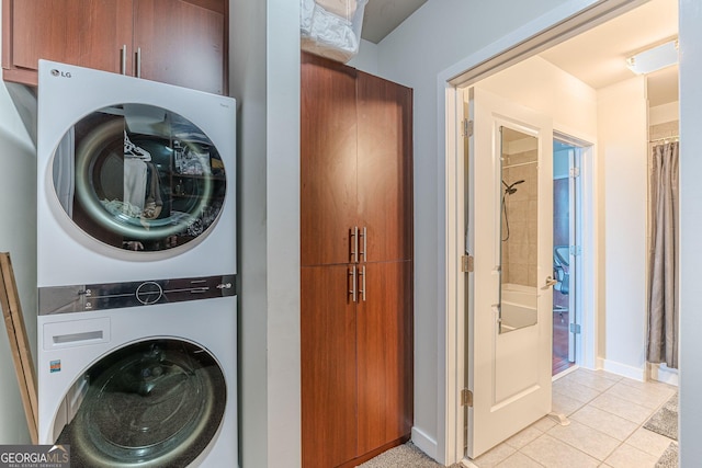 laundry room with light tile patterned floors, baseboards, and stacked washer and clothes dryer