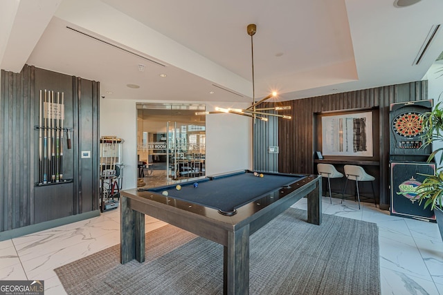 playroom with pool table, wood walls, an inviting chandelier, marble finish floor, and a raised ceiling