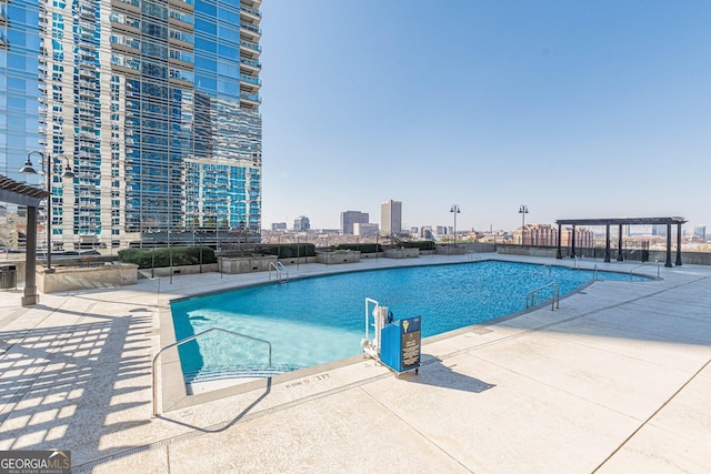 community pool with a city view, a patio area, and a pergola