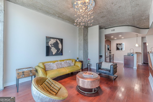 living room featuring a notable chandelier, visible vents, baseboards, and wood-type flooring