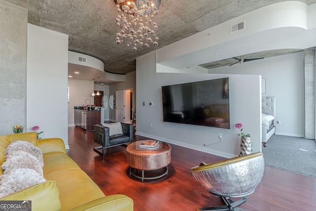 living room with visible vents, ceiling fan with notable chandelier, baseboards, and wood finished floors