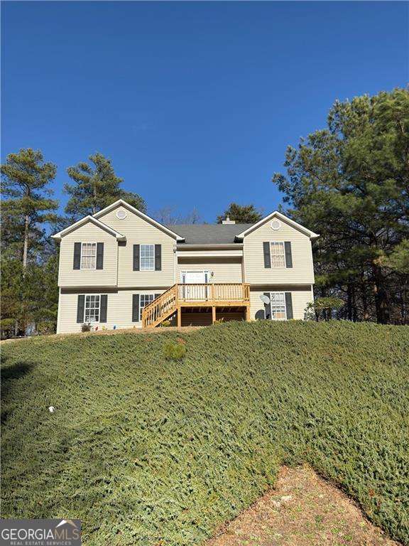 rear view of house featuring a wooden deck and a yard