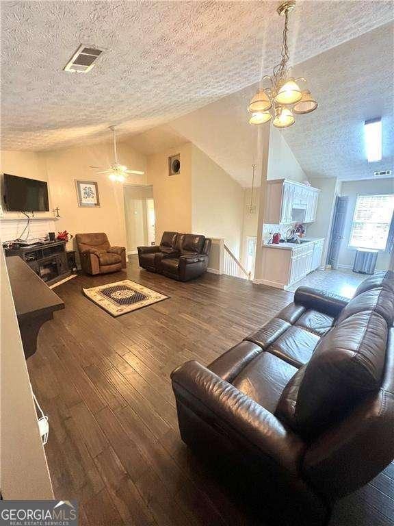 3672 Misty Oak Dr, Flowery Branch, GA 30542 - living area featuring vaulted ceiling, a textured ceiling, hardwood / wood-style floors, a ceiling fan, and a chandelier