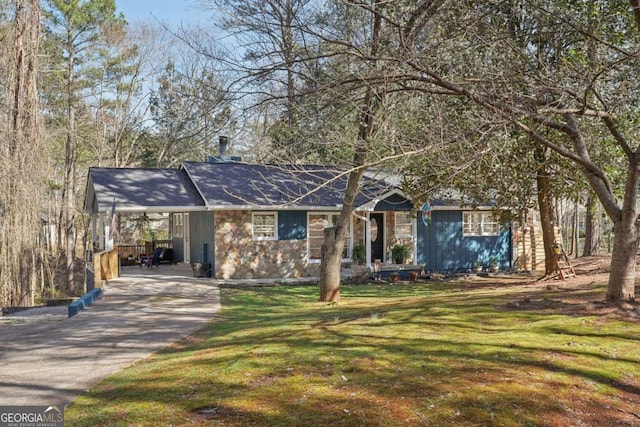 view of front of property with an attached carport, concrete driveway, a front lawn, and stone siding