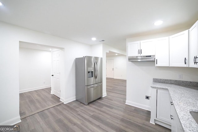 kitchen with under cabinet range hood, stainless steel fridge, wood finished floors, and white cabinetry