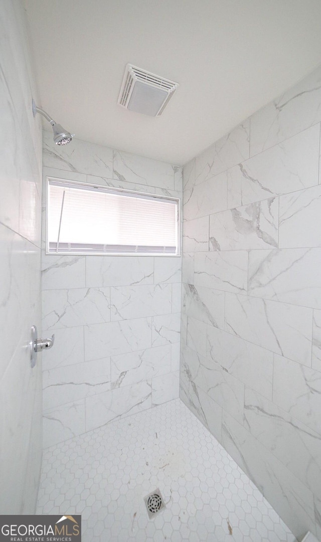 full bath with a tile shower and visible vents