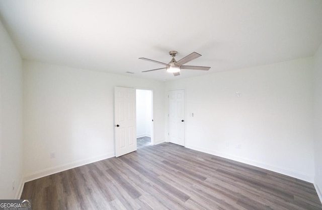 spare room featuring a ceiling fan, baseboards, and wood finished floors