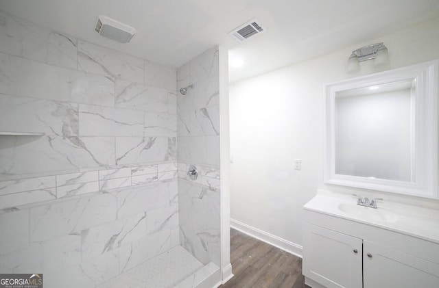 bathroom featuring visible vents, wood finished floors, baseboards, walk in shower, and vanity