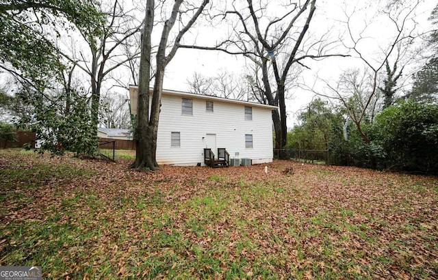 rear view of property with central AC unit and fence