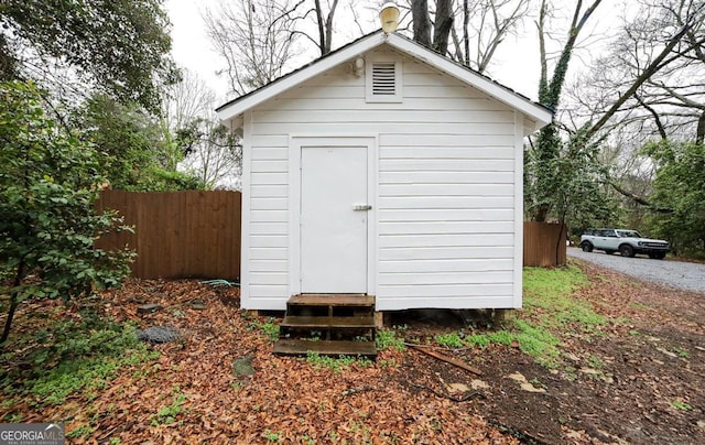 view of shed featuring entry steps and fence