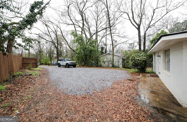 view of yard with gravel driveway and fence