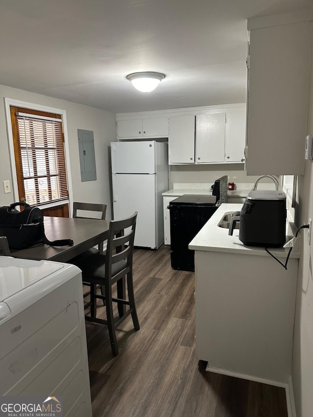 kitchen with electric panel, washer / clothes dryer, dark wood finished floors, freestanding refrigerator, and light countertops