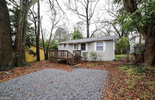 view of front of home featuring gravel driveway, a deck, and fence