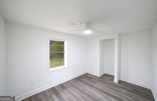 empty room with baseboards, dark wood finished floors, and a ceiling fan