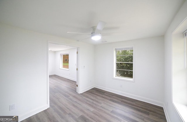 spare room with dark wood finished floors, a ceiling fan, and baseboards