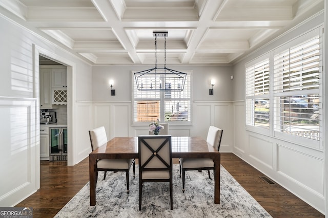 dining area featuring beamed ceiling, beverage cooler, dark wood finished floors, and a decorative wall