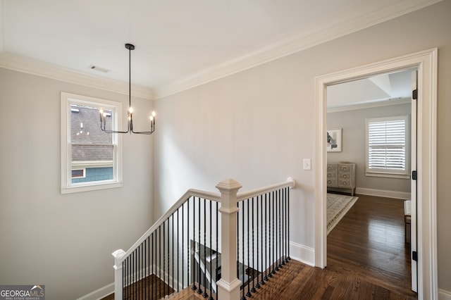 corridor featuring visible vents, baseboards, dark wood-style flooring, ornamental molding, and an upstairs landing