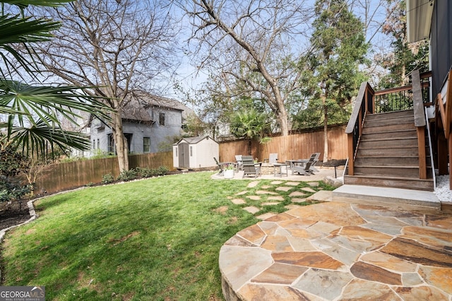 view of yard featuring stairway, a fenced backyard, an outdoor structure, a storage shed, and a patio area