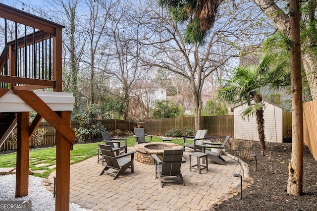 view of patio / terrace with an outdoor structure, a fenced backyard, a shed, and an outdoor fire pit