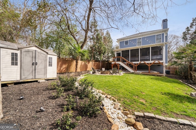 rear view of house featuring a fenced backyard, a sunroom, a chimney, an outdoor structure, and a storage unit