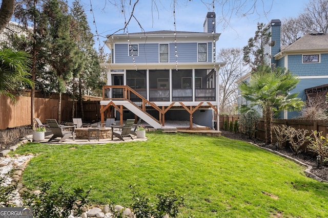 rear view of property with a patio, a fenced backyard, a yard, a fire pit, and a sunroom