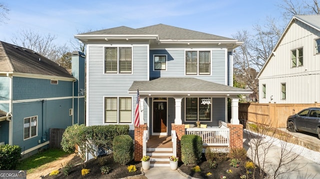 view of front of house featuring a porch, a shingled roof, and fence