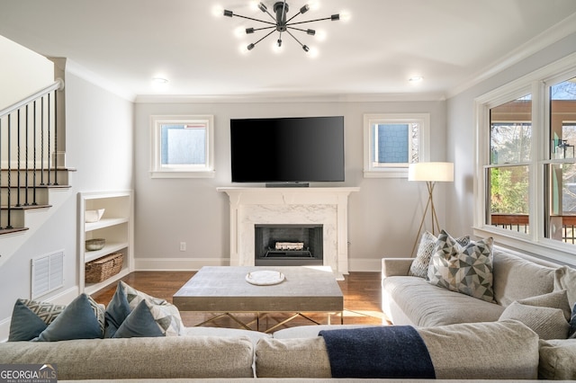 living area featuring a fireplace, wood finished floors, visible vents, and ornamental molding