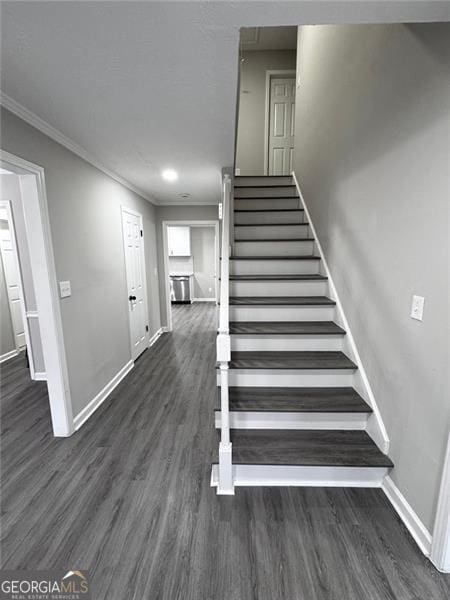 stairway with crown molding, baseboards, and wood finished floors