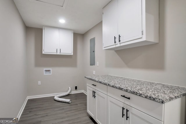 clothes washing area with electric panel, baseboards, cabinet space, and wood finished floors