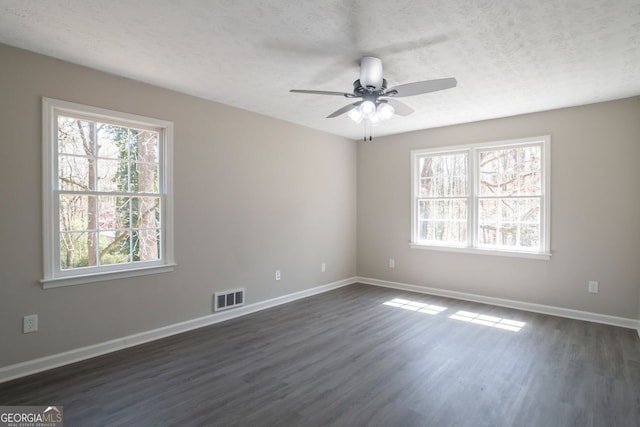 spare room featuring visible vents, a ceiling fan, a textured ceiling, dark wood finished floors, and baseboards